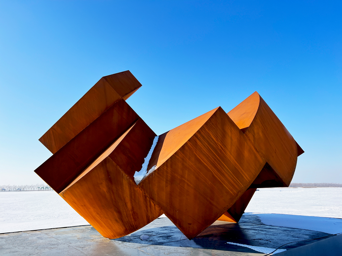 Œuvre en acier corten « Ascension horizontale » de Thierry Ferreira exposée sur une structure extérieure lors du symposium de sculpture de Hulan, montrant une composition horizontale monumentale dans un environnement urbain.