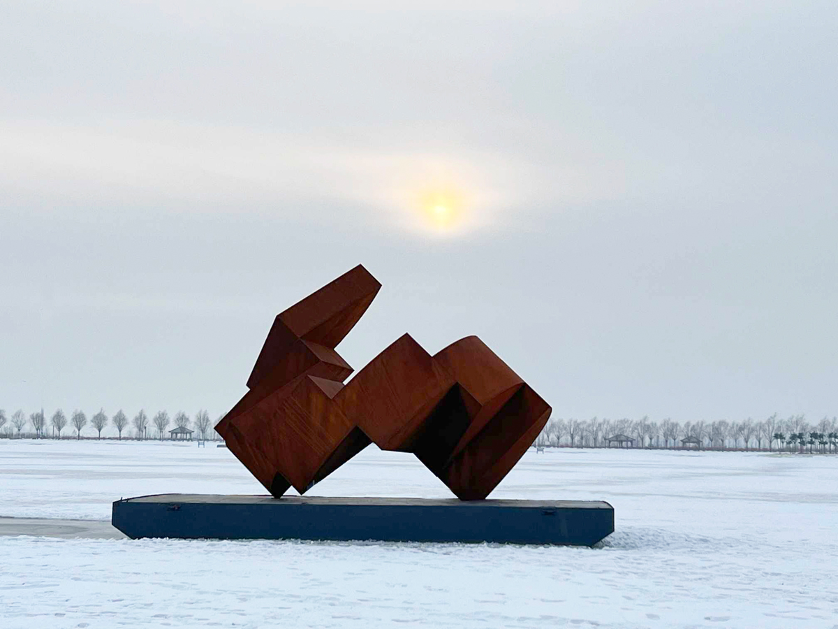 Œuvre en acier corten « Ascension horizontale » de Thierry Ferreira exposée sur une structure extérieure lors du symposium de sculpture de Hulan, montrant une composition horizontale monumentale dans un environnement urbain.