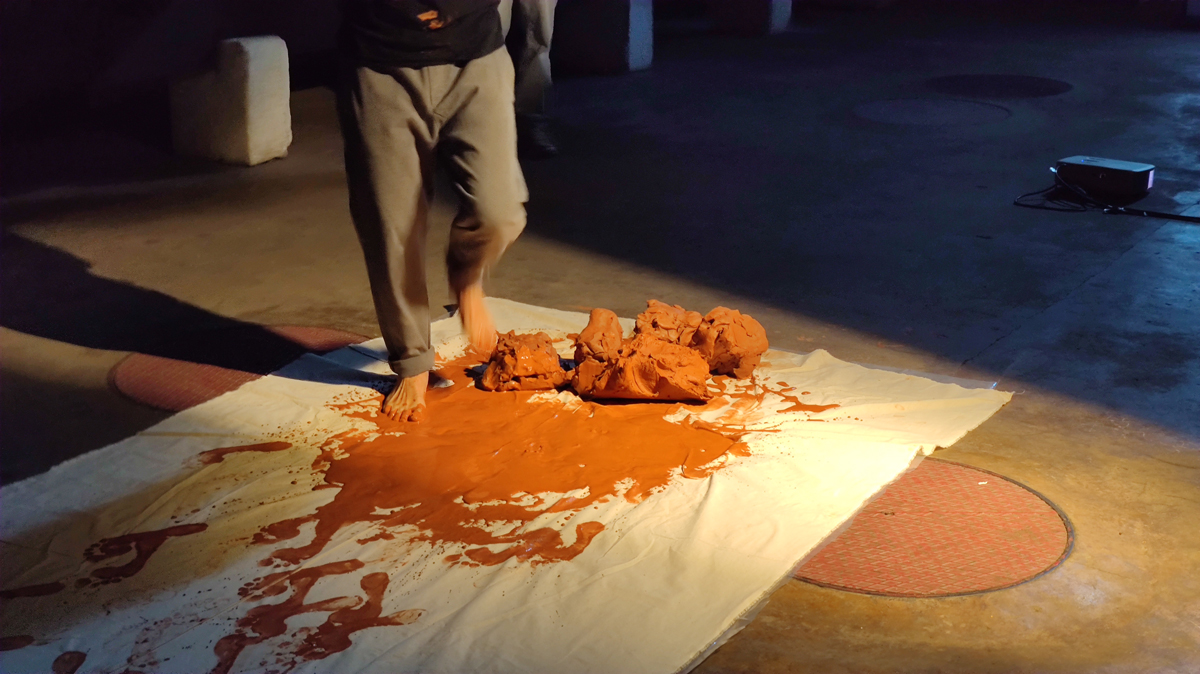 L’artiste Thierry Ferreira réalise la performance « Marcher sur la Terre » dans un espace muséal, en déplaçant de la terre de façon répétée pour construire une forme sculpturale qui enregistre le temps et le mouvement du corps.